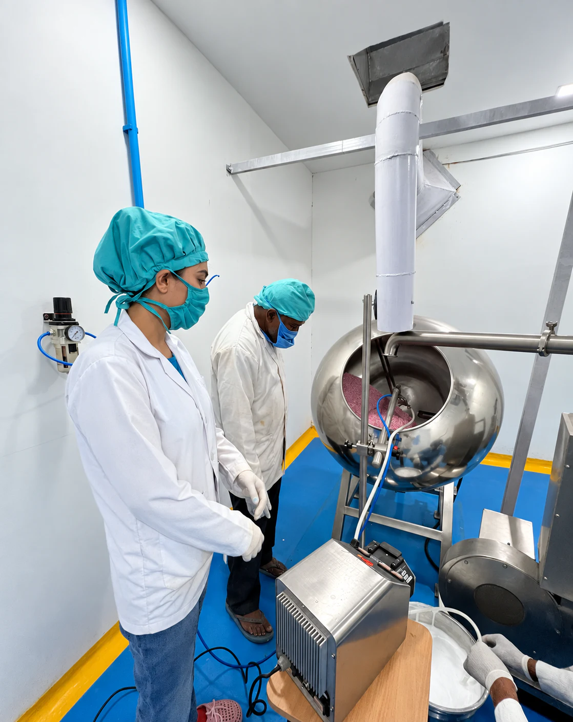 Two Healthy Health operators working beside stainless-steel coating equipment